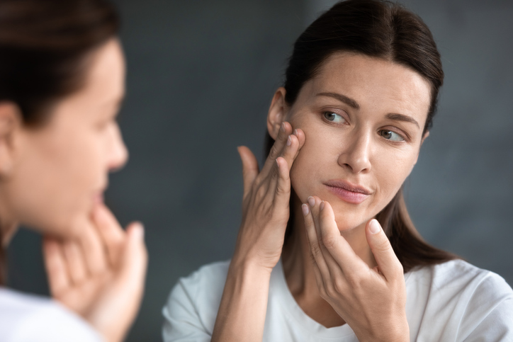 Woman checking face for acne in the mirror