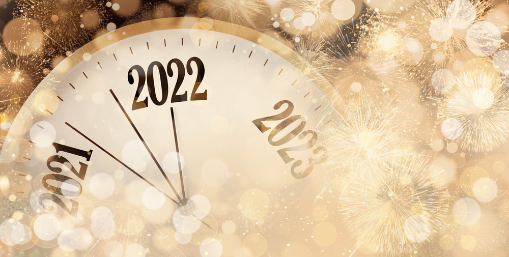 A picture of an old-style clock with the hands moving from 2021 to 2022 and golden sparkles in the foreground