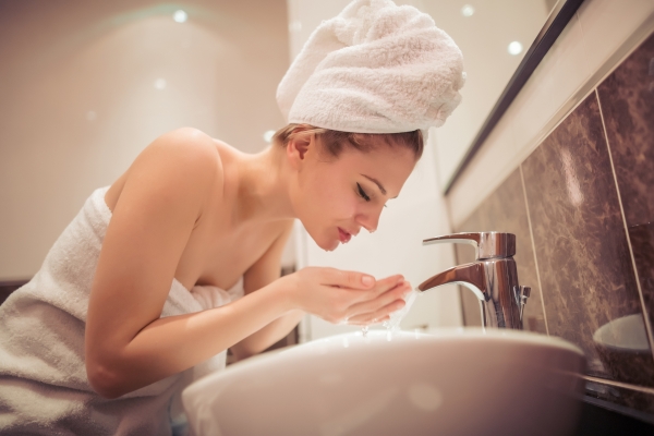 woman washing her face as part of her skin care regimen