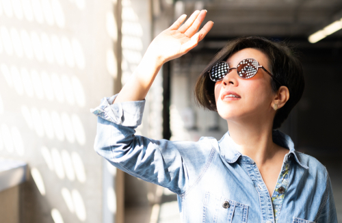 woman wearing 100% UV light eyes protection sunglasses, stand and raise her hand to block sunlight